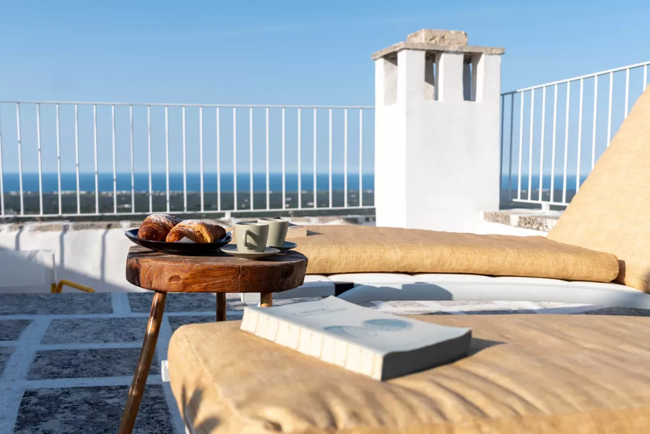 Terrazza panoramica con tavolino, cornetti e tazze, vista sul mare