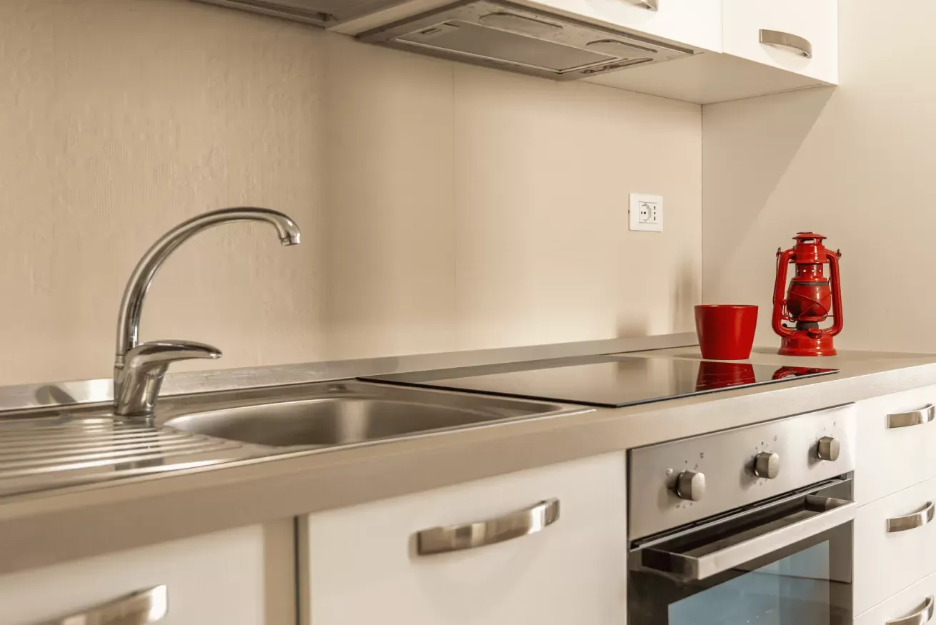 Cucina moderna con lavello, piano cottura e una lanterna rossa sul piano di lavoro