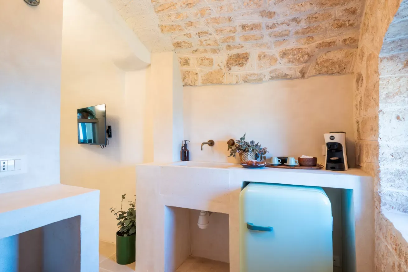 Angolo cucina con lavello, macchina del caffè e mini frigorifero in una stanza in pietra