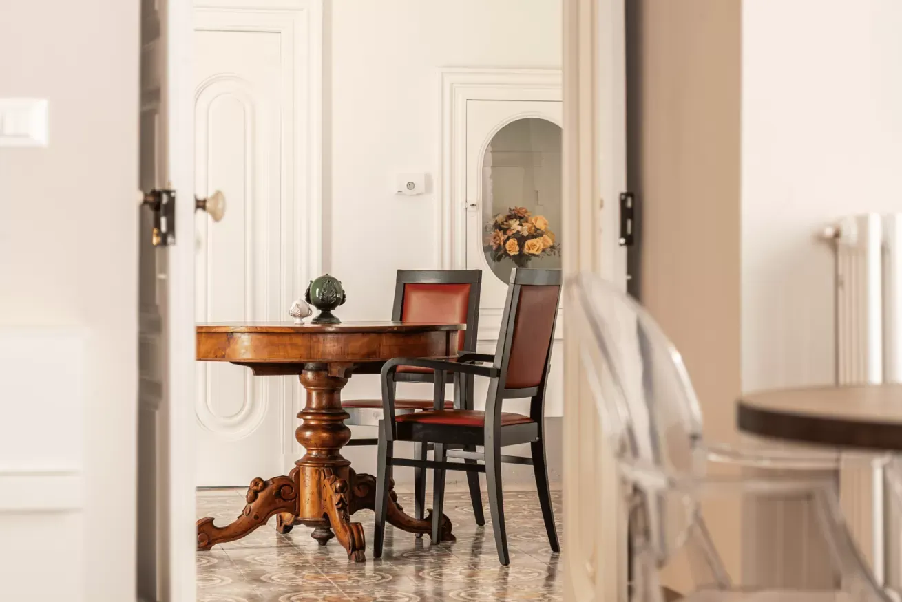 Sala da pranzo elegante con tavolo rotondo in legno e due sedie davanti a una porta ad arco