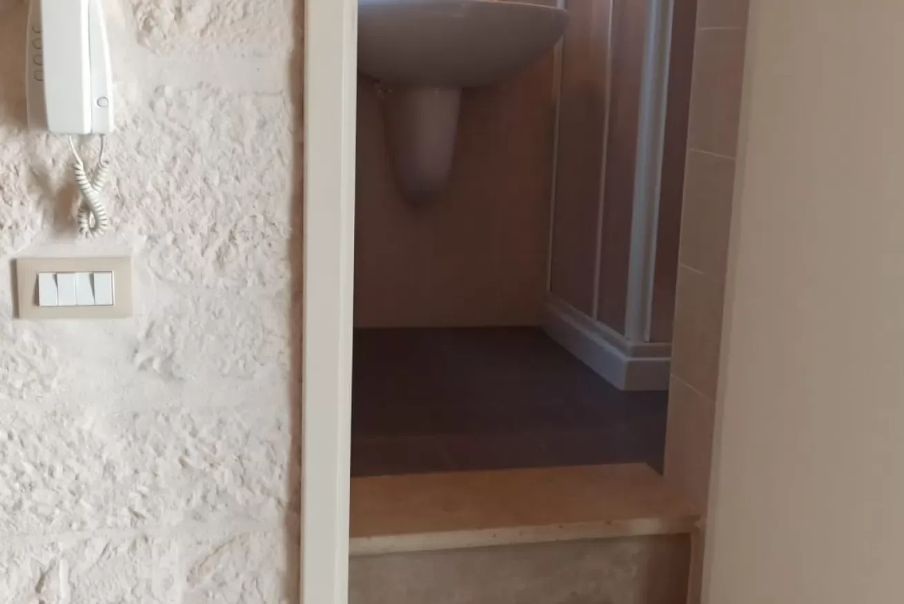 Ingresso di un bagno con lavabo e interruttori a parete